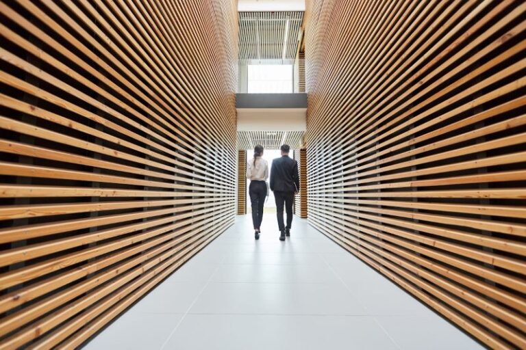 Modern irodai belső tér fa lamellás folyosóval, amely jól illusztrálja, hogy a fit-out támogatás hogyan segítheti az iroda személyre szabását és belső kialakítását.