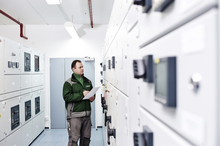 Műszaki szakember ellenőrzi egy irodaház elektromos és üzemeltetési rendszerét, amelynek költségei az üzemeltetési díjban is megjelenhetnek.