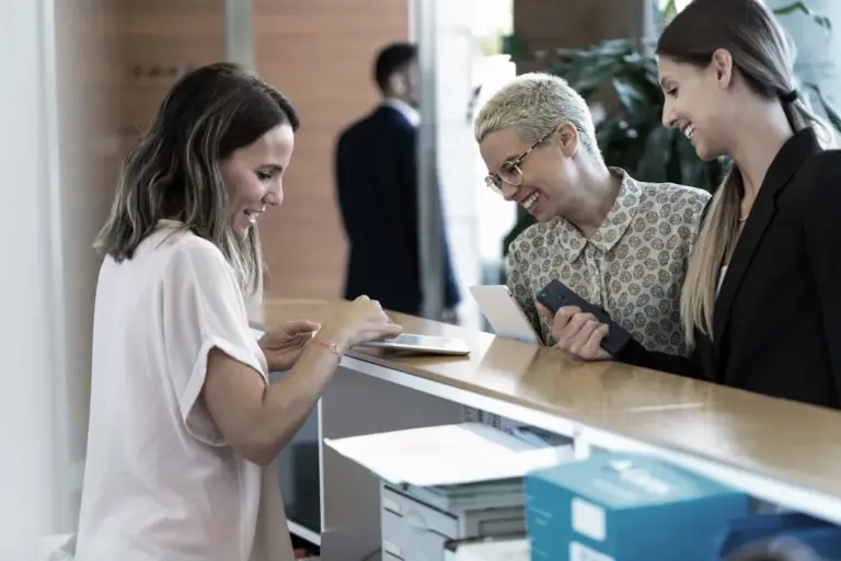 Recepciónál érkező ügyfelek egy modern irodában, amely a hozzáférhető iroda és az ügyféloldali komfort fontosságát mutatja be.