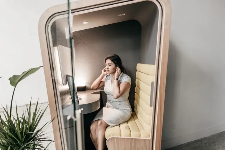 Telefonfülkében dolgozó nő, amely az iroda bérlés során a hibrid munkarendhez kapcsolódó tárgyaló- és meetingtér-igényeket mutatja be.